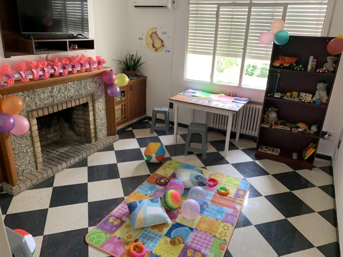Espacio de recreación en living de la casa, estufa a leña decorada, alfombra infantil con globos