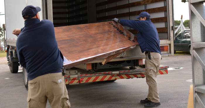 Personas cargando una placa grande de madera en un camión