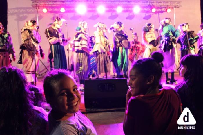 Club de Verano Cuenca Casavalle Tablado con murguistas y en primer plano una niña mira de frente a la cámara