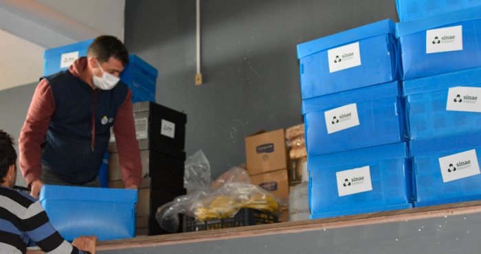 Persona con uniforma de Sinae acomodando cajas azules