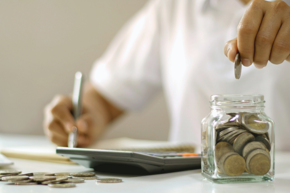 Persona poniendo una moneda en un frasco 