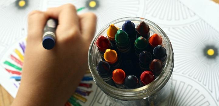 Niño dibujando en una hoja con crayones