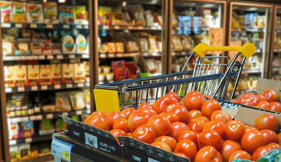 Góndola de supermercado con productos varios y en un primer plano el cajón de tomates