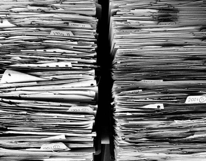 Decreto Nº 323/019 vista de papeles apilados en un estante