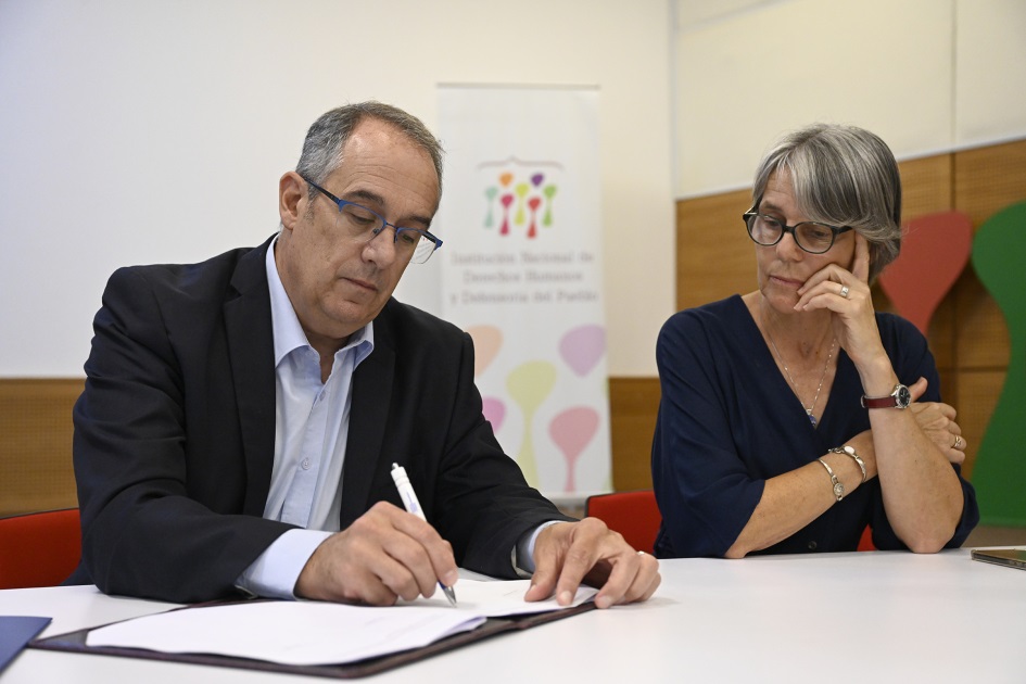 Ministro de Educación y Cultura firmando documentos junto a la presidenta del INDDHH d