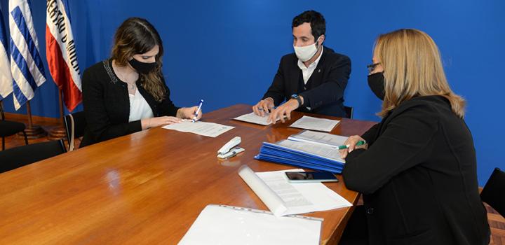 Persona beneficiaria de la beca, Director de Educación y encargada de la Oficina de becas firmando