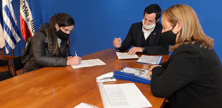 Persona beneficiaria de la beca, Director de Educación y encargada de la Oficina de becas firmando
