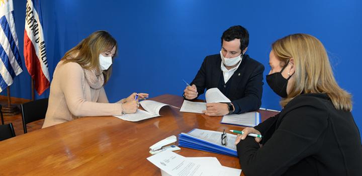 Persona beneficiaria de la beca, Director de Educación y encargada de la Oficina de becas firmando
