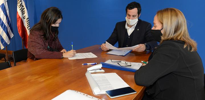 Persona beneficiaria de la beca, Director de Educación y encargada de la Oficina de becas firmando