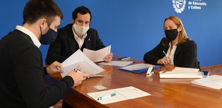Persona beneficiaria de la beca, Director de Educación y encargada de la Oficina de becas firmando