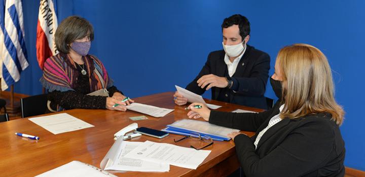Persona beneficiaria de la beca, Director de Educación y encargada de la Oficina de becas firmando