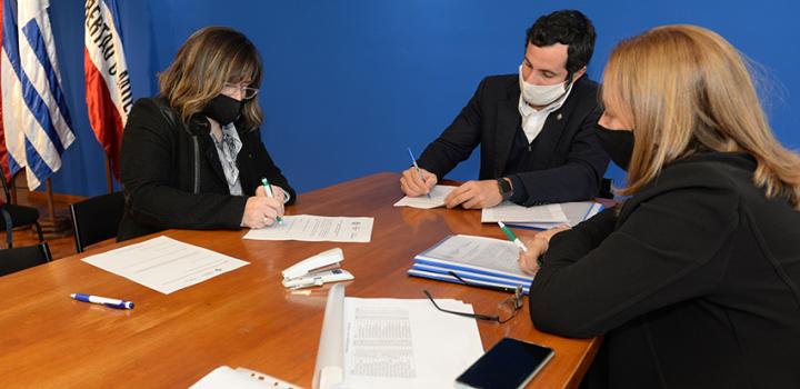 Persona beneficiaria de la beca, Director de Educación y encargada de la Oficina de becas firmando