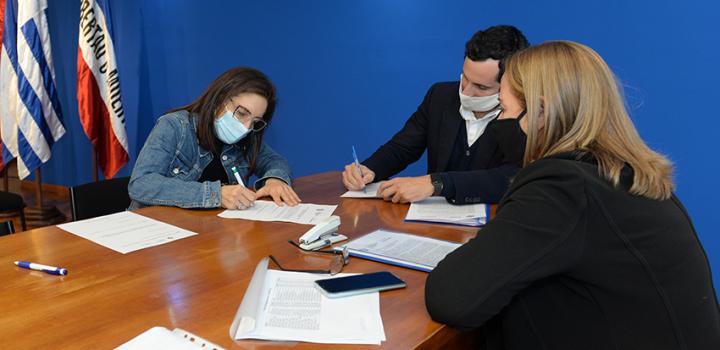 Persona beneficiaria de la beca, Director de Educación y encargada de la Oficina de becas firmando