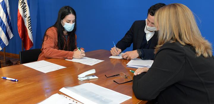 Persona beneficiaria de la beca, Director de Educación y encargada de la Oficina de becas firmando
