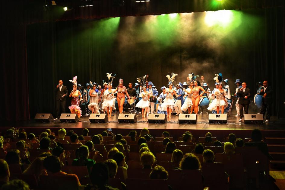 Público sentado mirando un murga en el escenario
