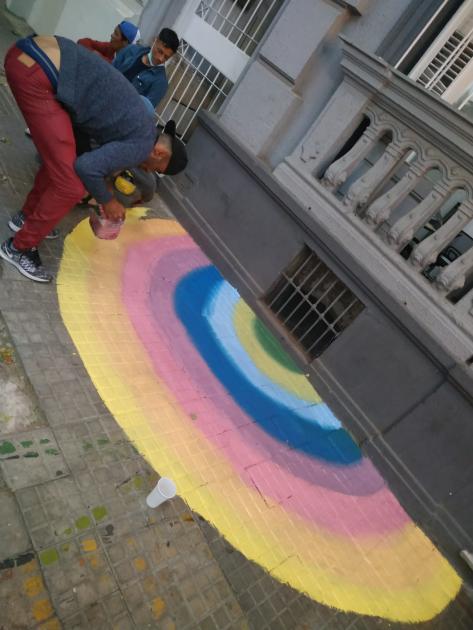 Persona pintando un arcoiris en la vereda