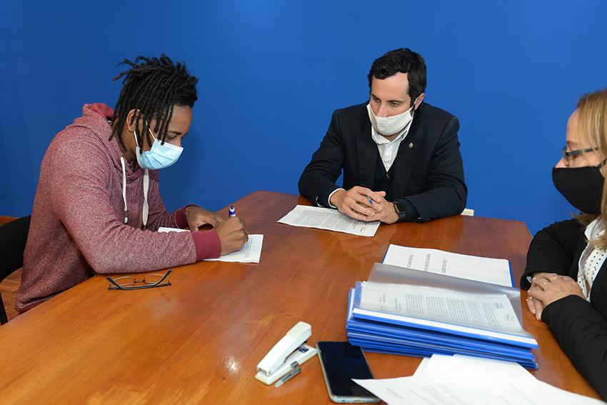Persona beneficiaria de la beca, Director de Educación y encargada de la Oficina de becas firmando e Persona beneficiaria de la beca, Director de Educación y encargada de la Oficina de becas firmando