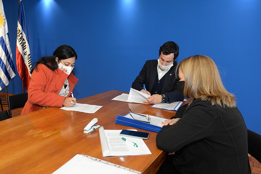 Persona beneficiaria de la beca, Director de Educación y encargada de la Oficina de becas firmando