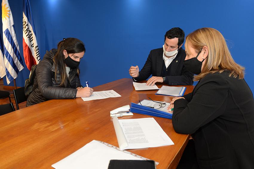 Persona beneficiaria de la beca, Director de Educación y encargada de la Oficina de becas firmando