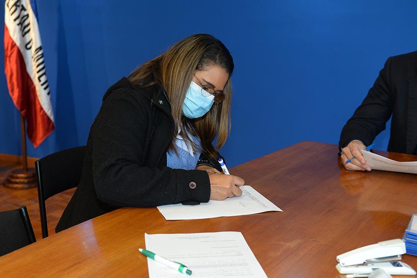 Persona beneficiaria de la beca firmando el contrato Persona beneficiaria de la beca firmando contrato