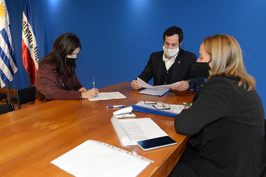 Persona beneficiaria de la beca, Director de Educación y encargada de la Oficina de becas firmando