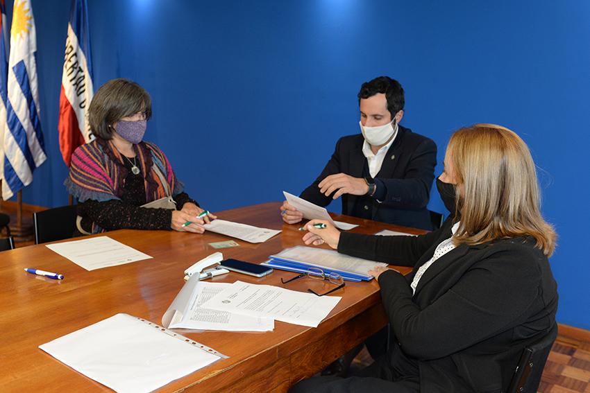 Persona beneficiaria de la beca, Director de Educación y encargada de la Oficina de becas firmando