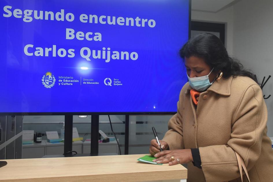 Una participante comparte reflexiones sobre la Beca. De fondo el cartel de bienvenida al Encuentro