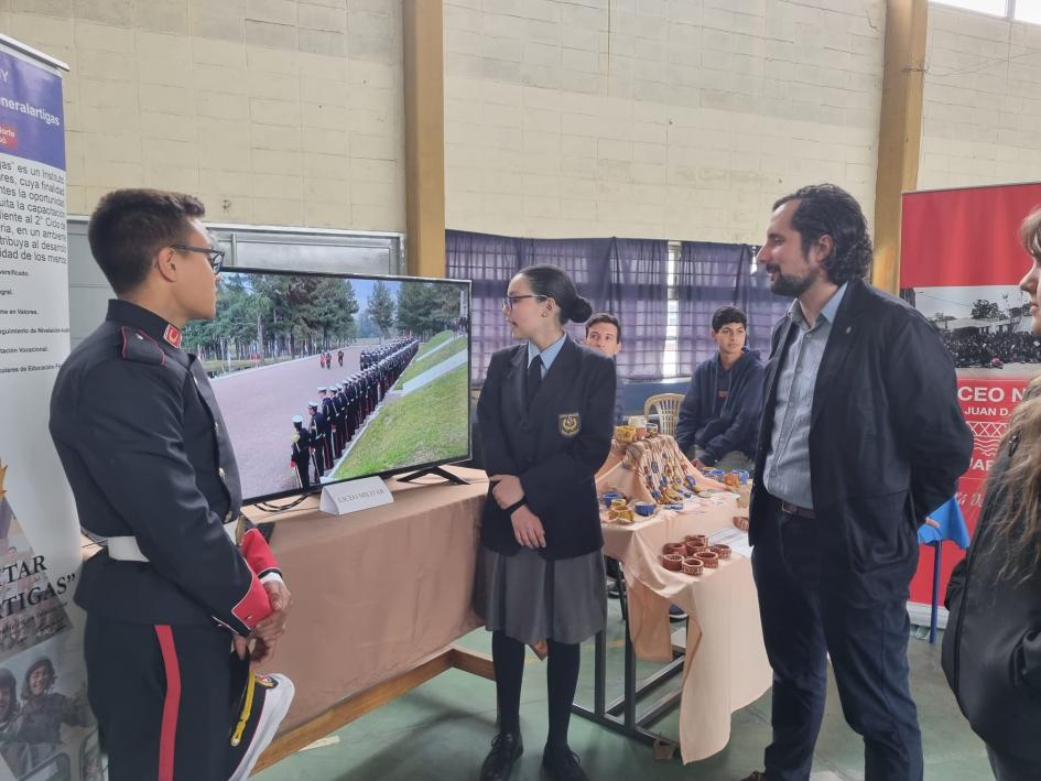 Director Baroni en Expo Educa en Liceo Nº2 de Tacuarembó Personas en ronda frente a una televisión