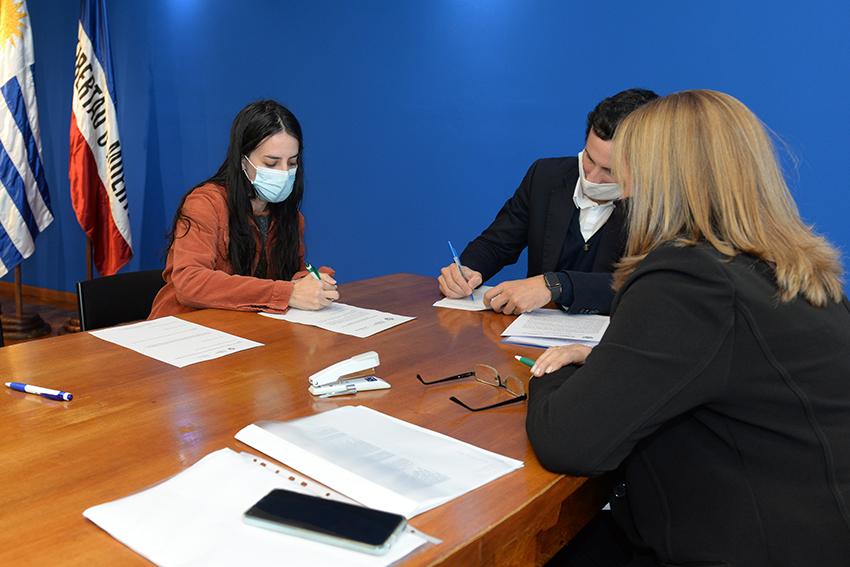 Persona beneficiaria de la beca, Director de Educación y encargada de la Oficina de becas firmando