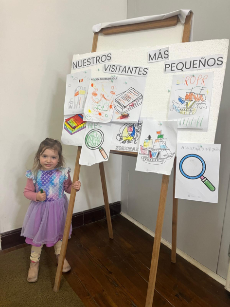 Niña con sus dibujos en cartelera