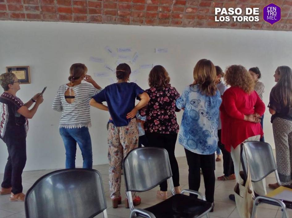 Personas participando de la actividad Mujeres de espalda mirando un pizzarrón