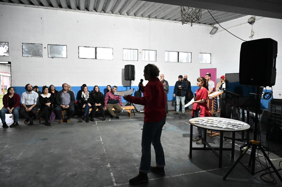 Educadora de PNEC hablando a la multitud con micrófono.