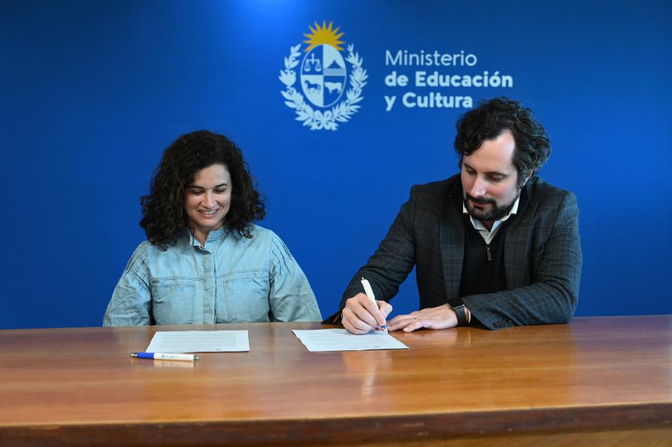 Gonzalo Baroni y beneficiaria firmando hojas