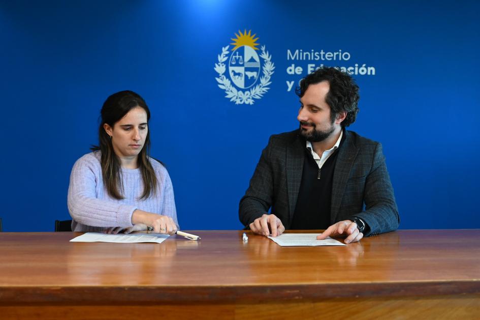 Gonzalo Baroni y beneficiaria firmando hojas