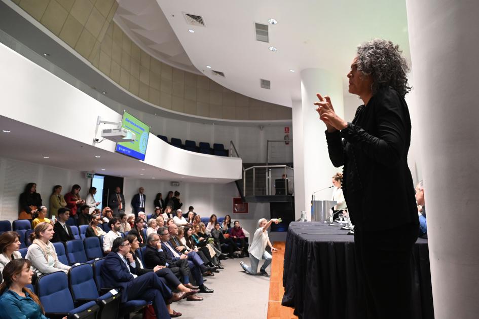 Intérprete en Lengua de Señas Uruguaya durante la conferencia, de fondo se ve la audiencia sentada