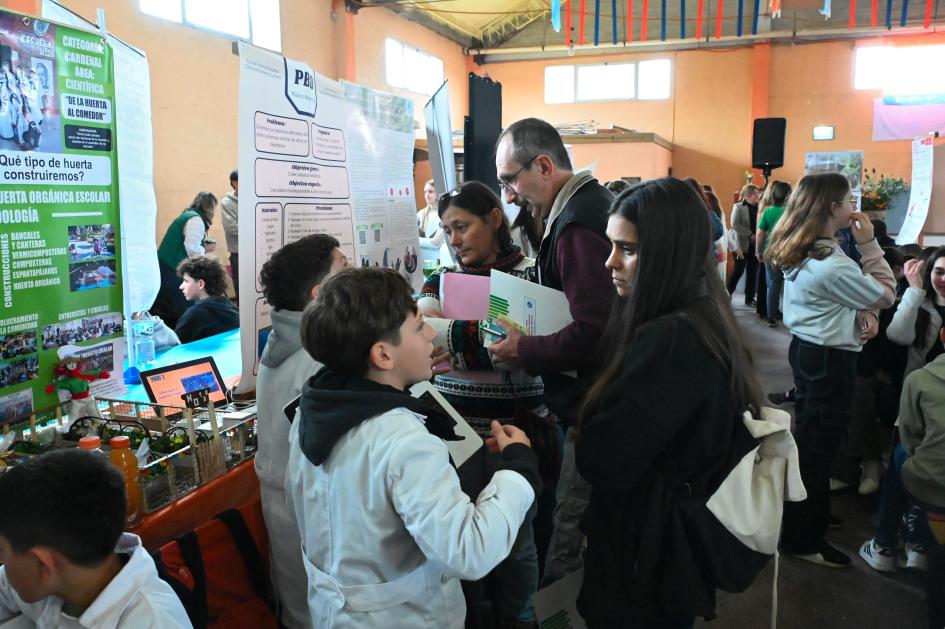 Un niño escolar habla explica para una mujer su proyecto de la Feria de Ciencia