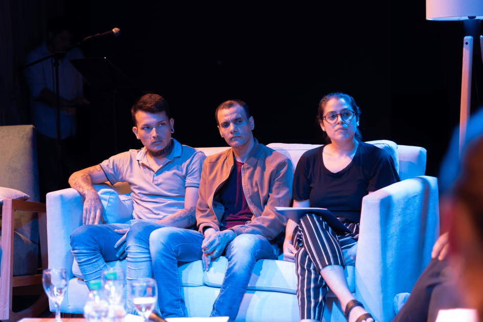 Tres personas sentadas en un sillón en un escenario