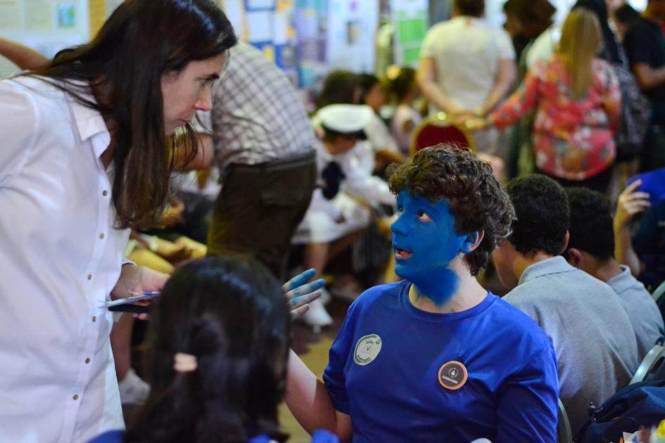 Maestra hablando con un niño que tiene la cara pintada de azul