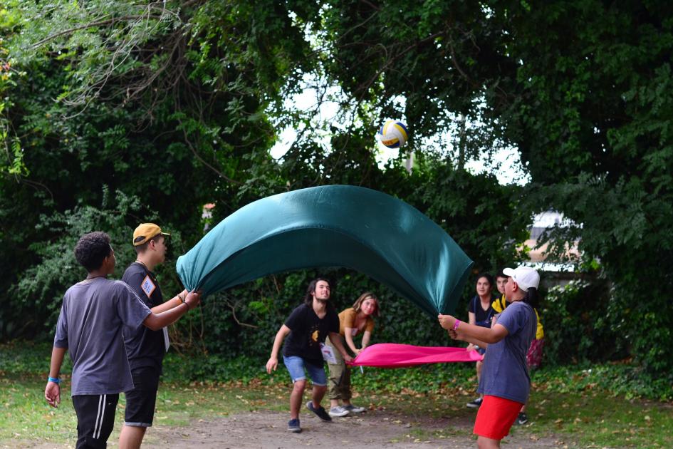 Niños jugando con una gran tela y pelota