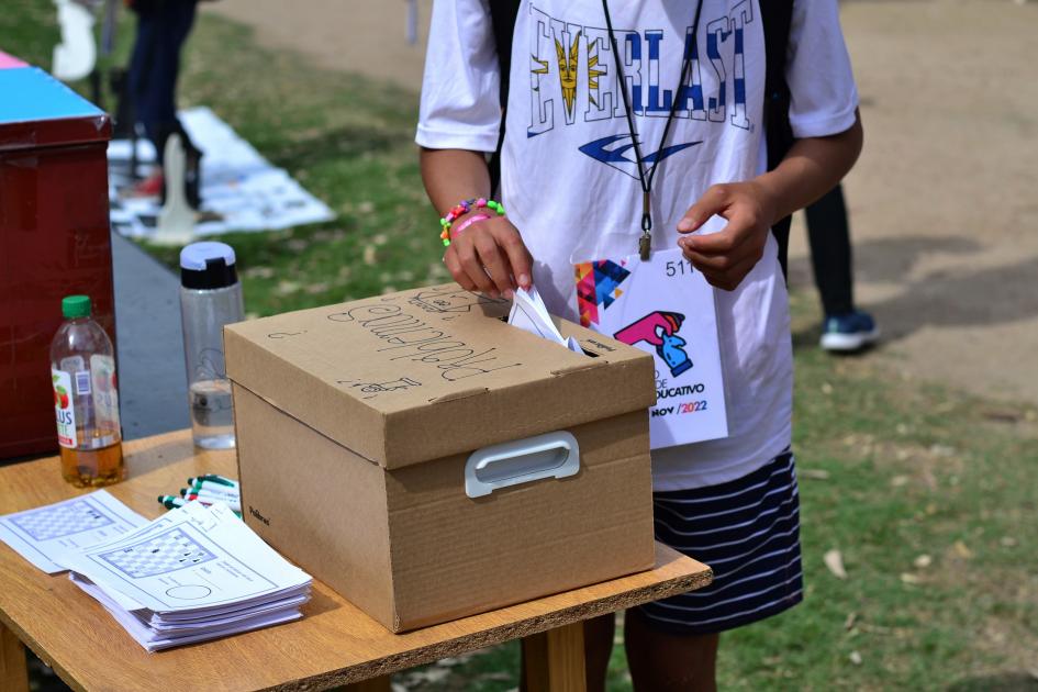 Un niño metiendo un sobre dentro de una urna