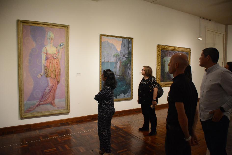 Personas de pie frente a una pintura