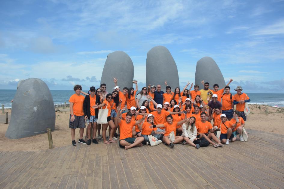 30 personas posando para una foto con los Dedos de Punta del Este