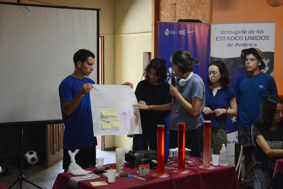 Jóvenes haciendo una presentación con una cartulina