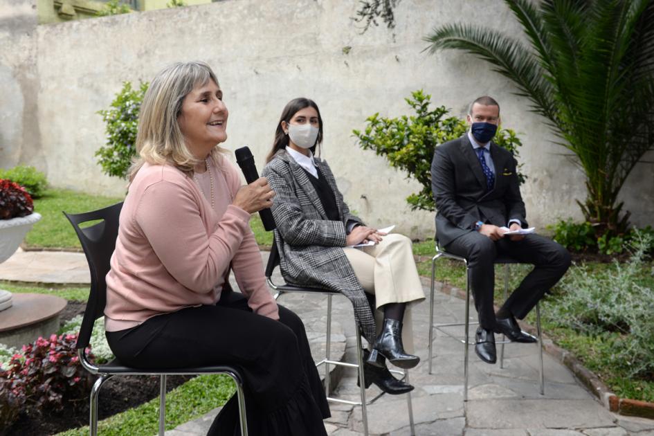 Mujer sentada hablando con micrófono.