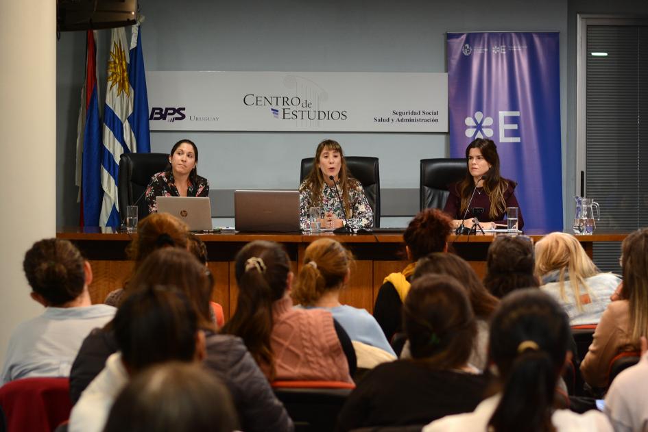 Las tres disertantes del curso, sentadas frente al público. Una de ellas habla por micrófono.