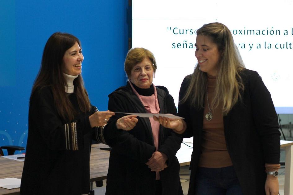 Rosario Rodríguez de la DNE entrega certificado de aprobación a una participante junto a Cherro DGS