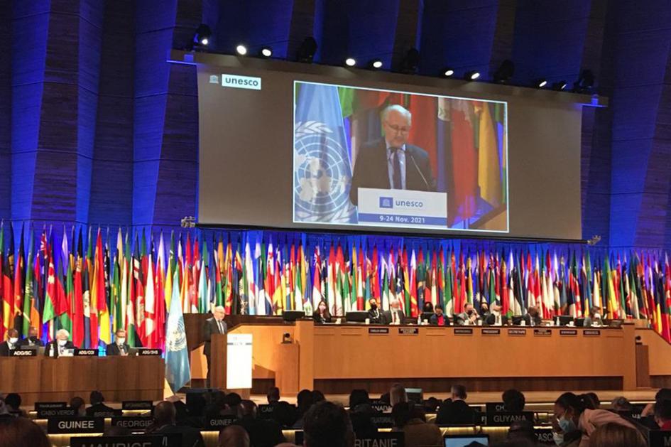 Sala de conferencias con las banderas de los participantes de la Unesco y la pantalla