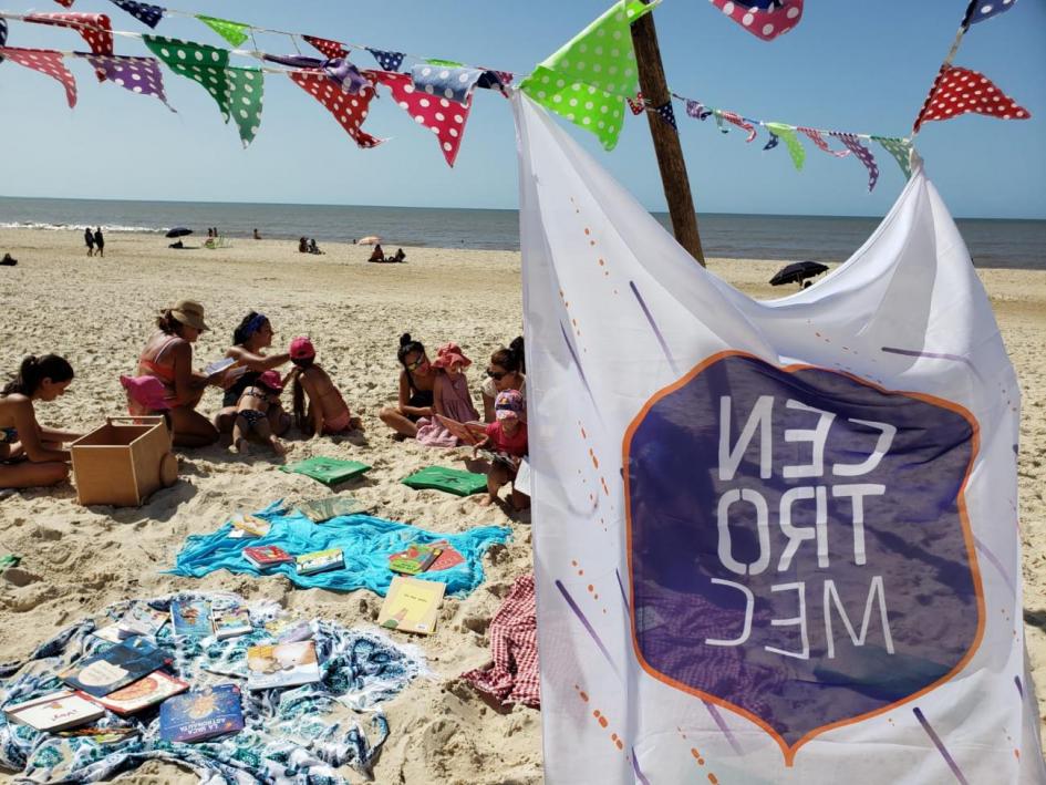 Bandera de Centros MEC y de fondo niños, niñas y jóvenes en la playa