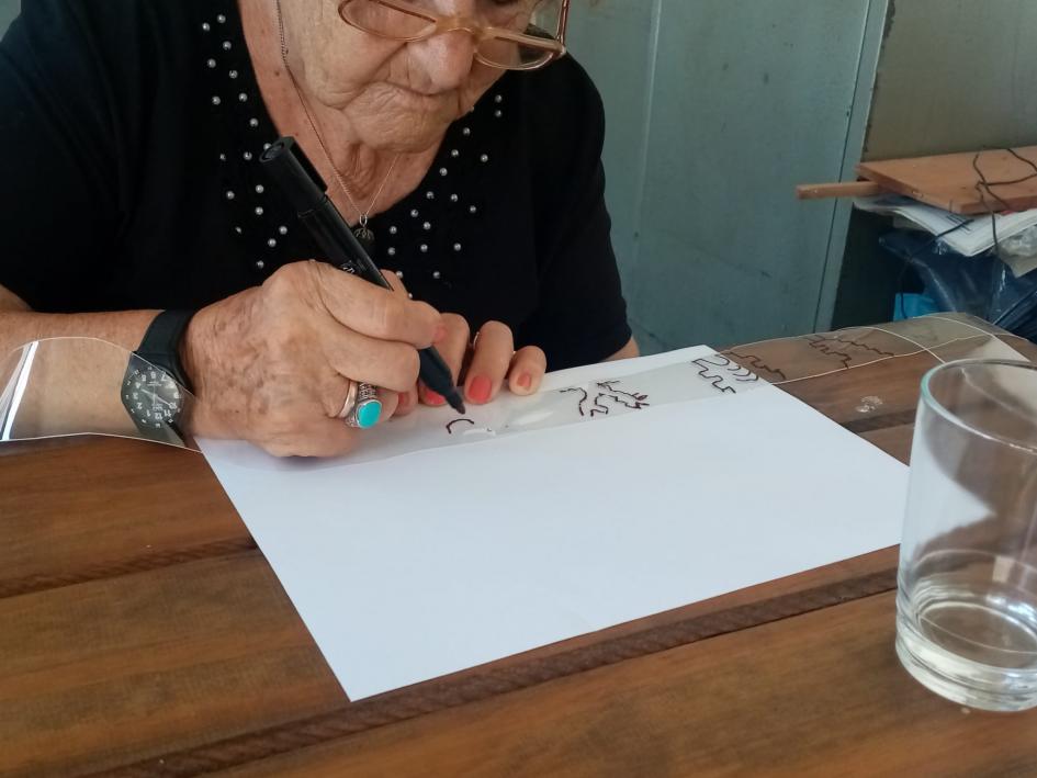 Persona mayor dibujando sobre un retazo de plástico