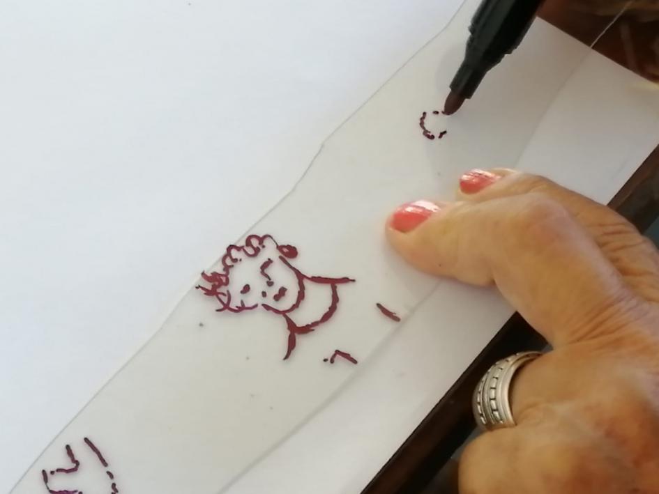 Taller audiovisual Dos manos dibujando un rostro sobre un retazo de plástico